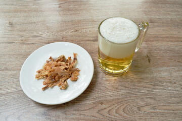 baked dry salty squid slice on plate eat couple with cold beer on table