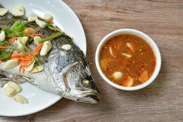 steamed bass fish with garlic dipping spicy sauce on table