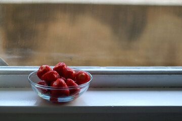 Bowl of strawberries on a window sill. Selective focus.