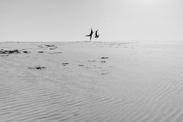 young couple a guy and a girl with joyful emotions in black clothes walk through the white desert