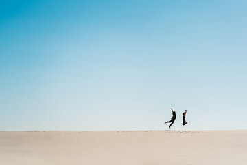 Fototapeta na wymiar young couple a guy and a girl with joyful emotions in black clothes walk through the white desert