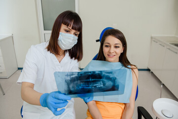 Young woman dentist explaining to her patient on a dental x-ray panoramic radiography all the dental treatment that needs to do in dentistry