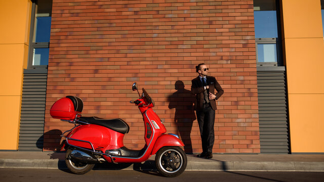 Man in classic suit near a red vintage scooter