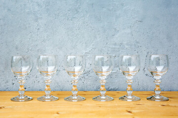row of wine glasses on wooden table with grey background