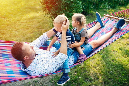 Young father with two kids having fun in hammock. Father's day, family day, children's day concept.