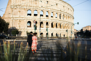 The couple is walking in Rome near the Colosseum.
