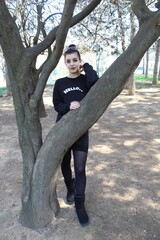 Portrait of a young girl behind a tree outside