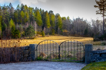 A gate leading to a church yard with meadow and trees in background at spekeroed church