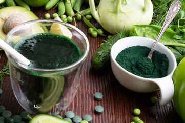 detox green cocktail with spirulina around vegetables.  lifestyle  concept. various fresh green...