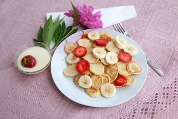 Tasty trendy breakfast - mini cereal pancakes with strawberry, banana and sugar powder.