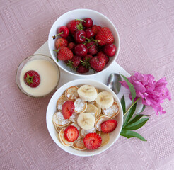 Tasty trendy breakfast - mini cereal pancakes with cherries,strawberries, banana, condensed milk  and sugar powder. 
Breakfast is popular during quarantine. Handmade pink tablecloth and pink peonies