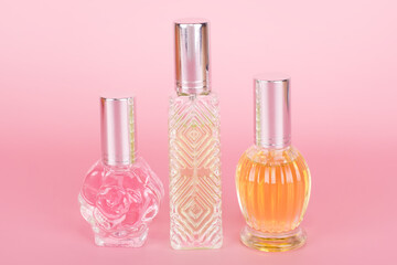Different transparent perfume bottles on pink background. Aromatic essence bottles. Perfumery, cosmetics, fragrance collection. Free space for text.