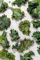 Close-up of white baking paper with veggie kale chips with pepper and olive oil.Low-carb and gluten free vegetable crisps snack.Top view