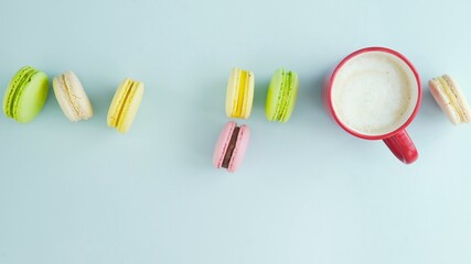 Macaroons or macaron on pastel blue surface with espresso in white cup.