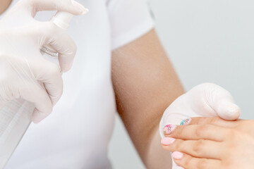 Close up of manicurist moisturising fingernails of woman by thermal water.