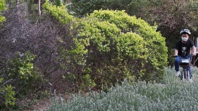 Child with mask cycling for exercise in coronavirus pandemic, Beijing, China