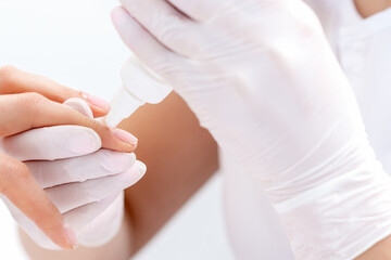 Manicure specialist hands are applying glue for nail of woman close up. Manicurist uses manicure tool.