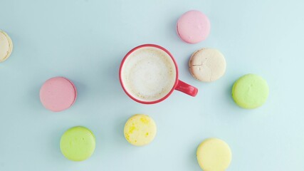 Macaroons or macaron on pastel blue surface with espresso in white cup.