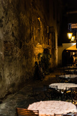 selective focus of bicycle near old wall and tables with chairs on terrace