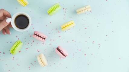 Macaroons or macaron on pastel blue surface with espresso in white cup.