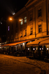 Fototapeta na wymiar dark street and silhouette of people sitting in cafe with terrace