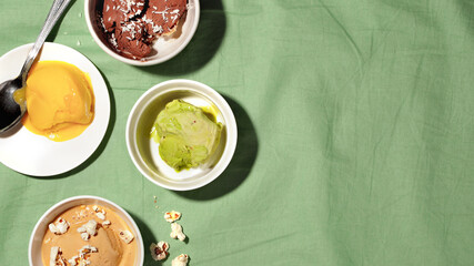 Bowls of various vegan sugar free sorbet ice cream scoop on green background top view copy space.Healthy dessert concept