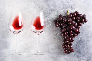 Minimalistic flat lay composition with two glasses of vintage red wine and bunch of grapes on grunged concrete table background. Expensive cabernet sauvignon concept. Copy space, top view. - obrazy, fototapety, plakaty