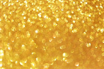 Golden sparkle glitters with bokeh effect and selectieve focus. Festive background with bright gold lights, champagne bubble. Christmas mood concept. Copy space, close up, texture, top view.