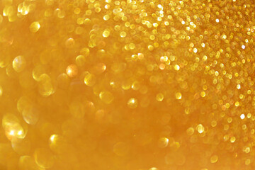 Golden sparkle glitters with bokeh effect and selectieve focus. Festive background with bright gold lights, champagne bubble. Christmas mood concept. Copy space, close up, texture, top view.