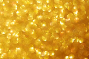 Golden sparkle glitters with bokeh effect and selectieve focus. Festive background with bright gold lights, champagne bubble. Christmas mood concept. Copy space, close up, texture, top view.