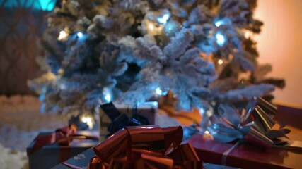 Dolly vertical panning shot from blue X-mas present box with red bow to Christmas tree top. New Year's Eve Gift expectation concept. - Powered by Adobe