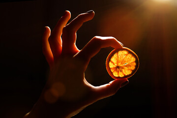 Hand holding a piece of dried orange in beautiful backlight