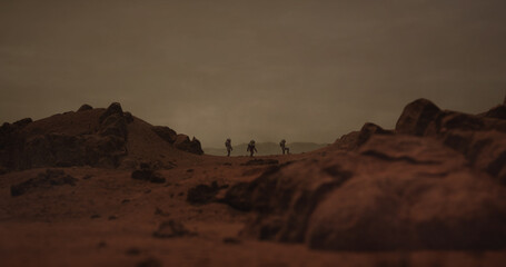 Three astronauts walking on a surface of a red rocky planet. Mars colonization concept. Planet created in 3D © supamotion