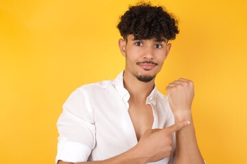 Handsome young man over isolated background In hurry pointing to watch time, impatience, upset and angry for deadline delay