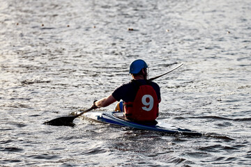 A guy wearing a helmet on a canoe polo rowing a paddle and sailing on water. canupolo. puts on a...