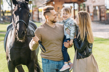Young family on a horse ranch. People have a fun with a horse.