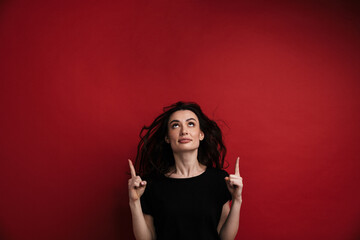Photo of attractive woman in casual t-shirt pointing fingers upward