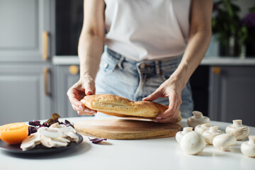 Girl breaks bread with her hands in the bright kitchen. Healthy food.