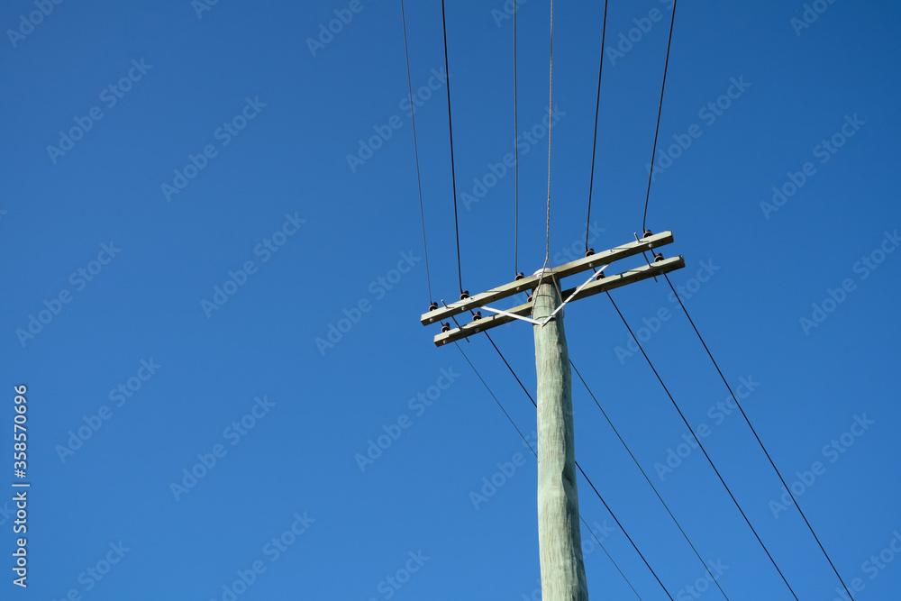 Wall mural wooden electric pole with blue sky background, copy space.