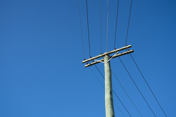 Wooden electric pole with blue sky background, copy space.