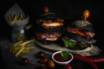 Close-up of burgers and fries in a bucket on a dark background with tomato sauce
