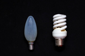 Energy-saving halogen lamp and ordinary incandescent lamp on a black background. Electricity Saving...