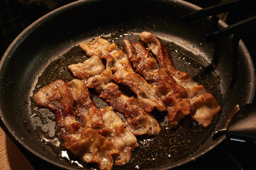 Fried crispy bacon in a close-up pan on top horizontally 