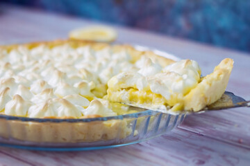 Lemon tart with meringue topping on plate. Pie on vintage cake spatula. Cake with lemon curd.