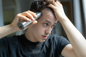 Young man giving himself a haircut