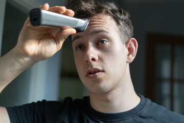 Young man giving himself a haircut