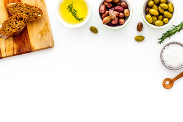 Mediterranean olives near bread on cutting board top view copy space