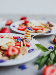Pancake cereal, trendy food. Mini cereal pancakes with butter, honey, and strawberries.