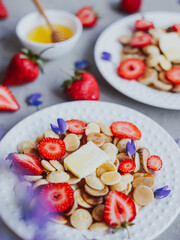 Pancake cereal, trendy food. Mini cereal pancakes with butter, honey, and strawberries.