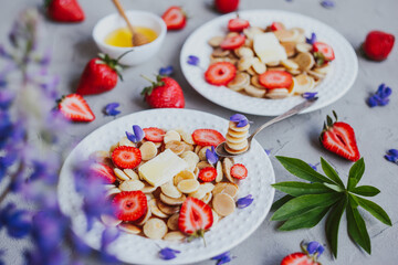 Pancake cereal, trendy food. Mini cereal pancakes with butter, honey, and strawberries.